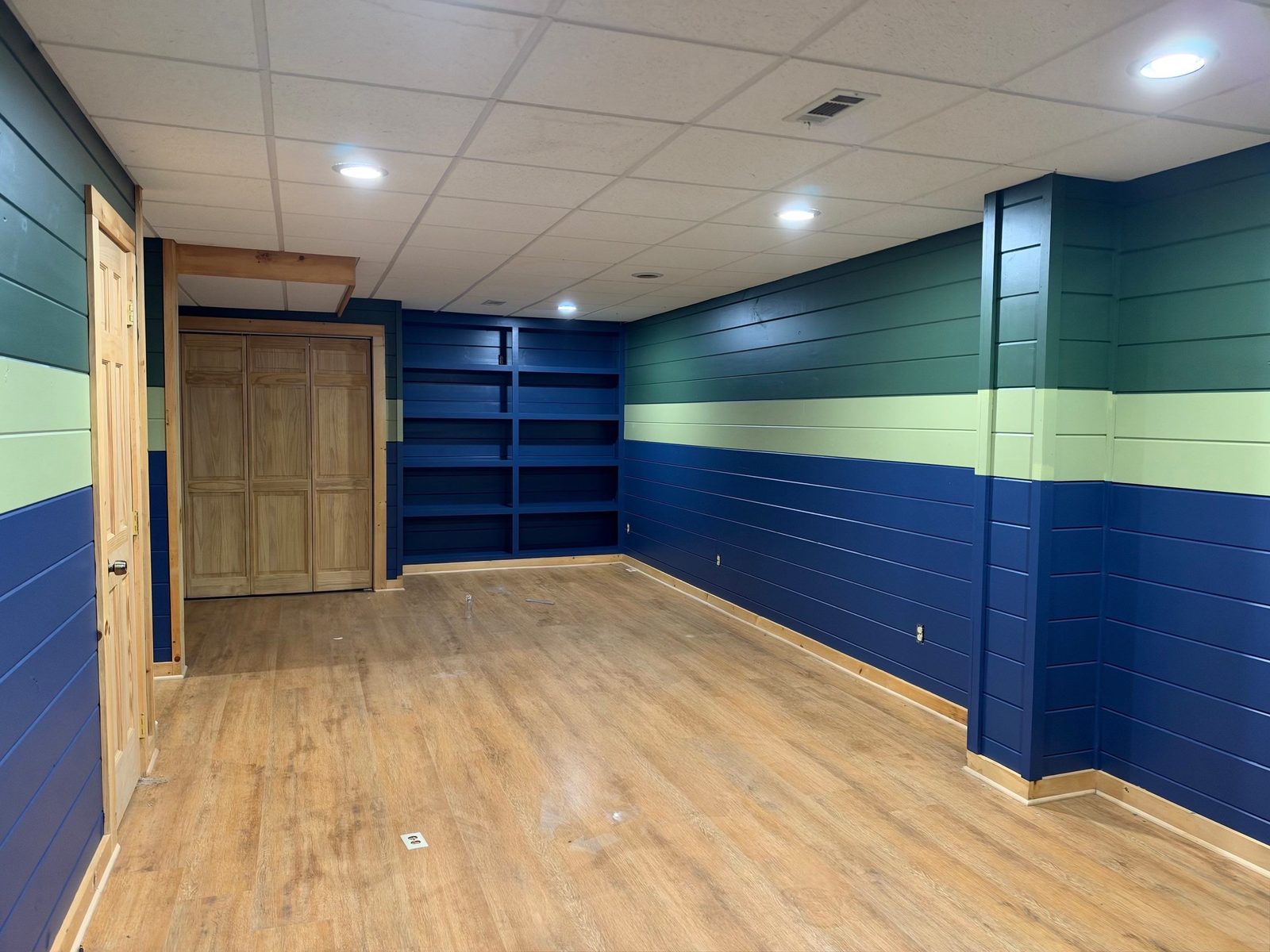 Blue Ridge cabin basement with navy built-in shelves and green, sage and navy striped shiplap walls