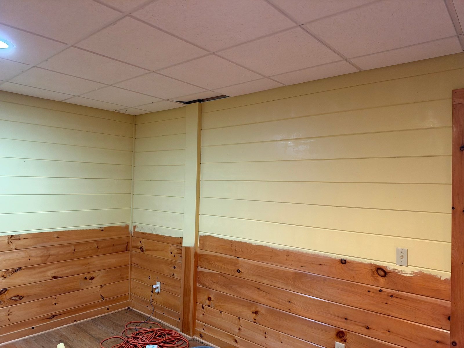 Basement shiplap in a Blue Ridge cabin before painting, pale yellow upper walls and raw pine lower walls