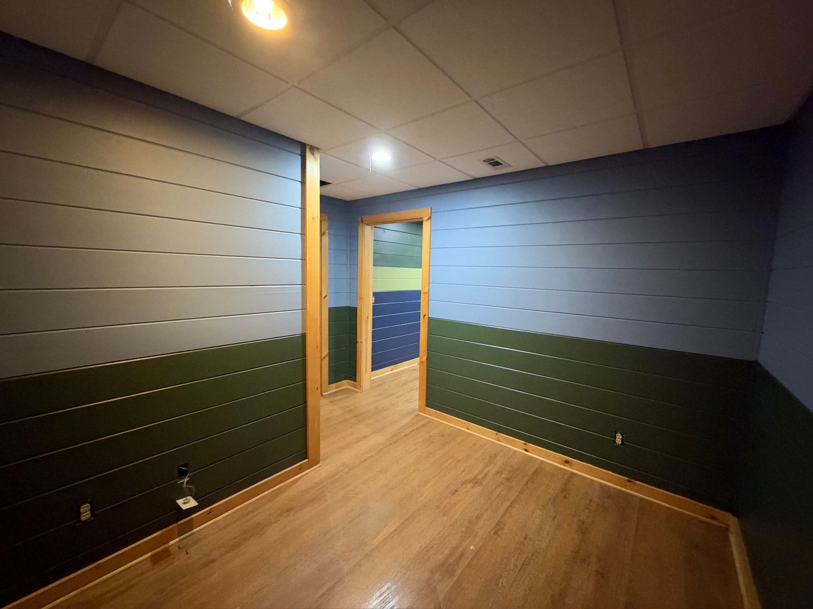 Two-tone basement shiplap in a Blue Ridge cabin, blue-gray above and dark green below