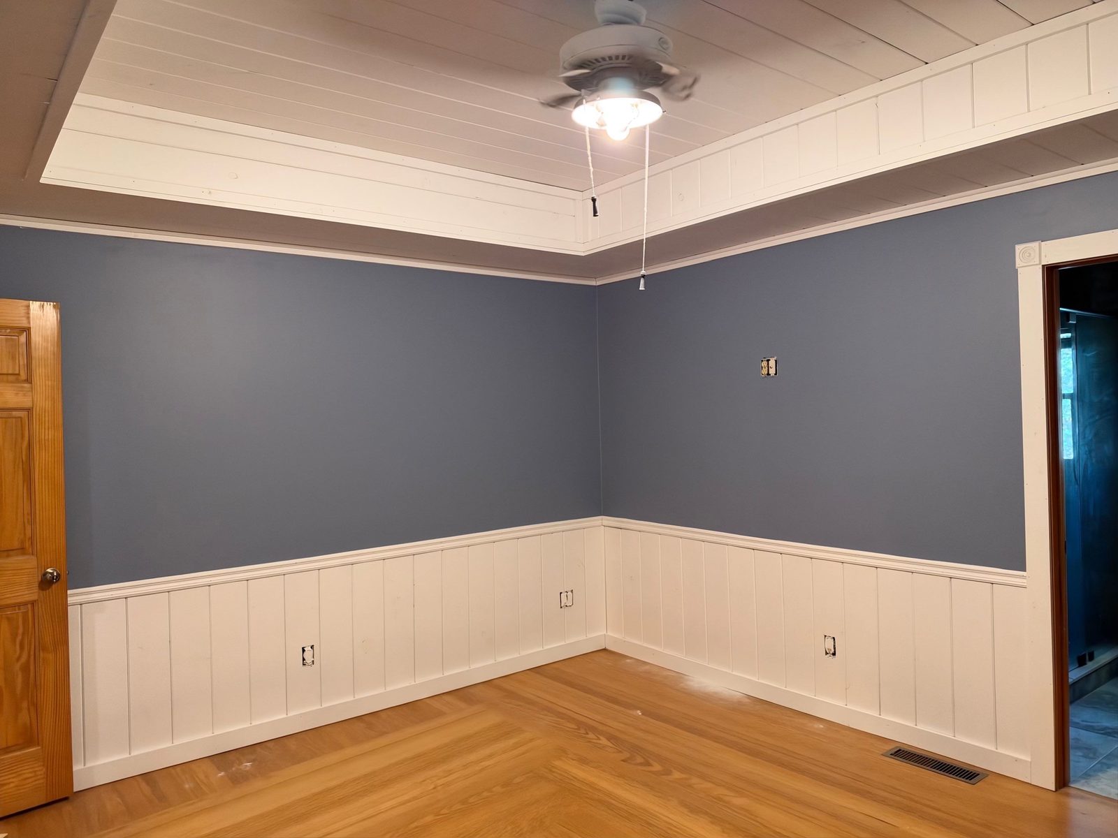Blue Ridge cabin bedroom painted blue-gray with a white tray ceiling and white vertical plank wainscot