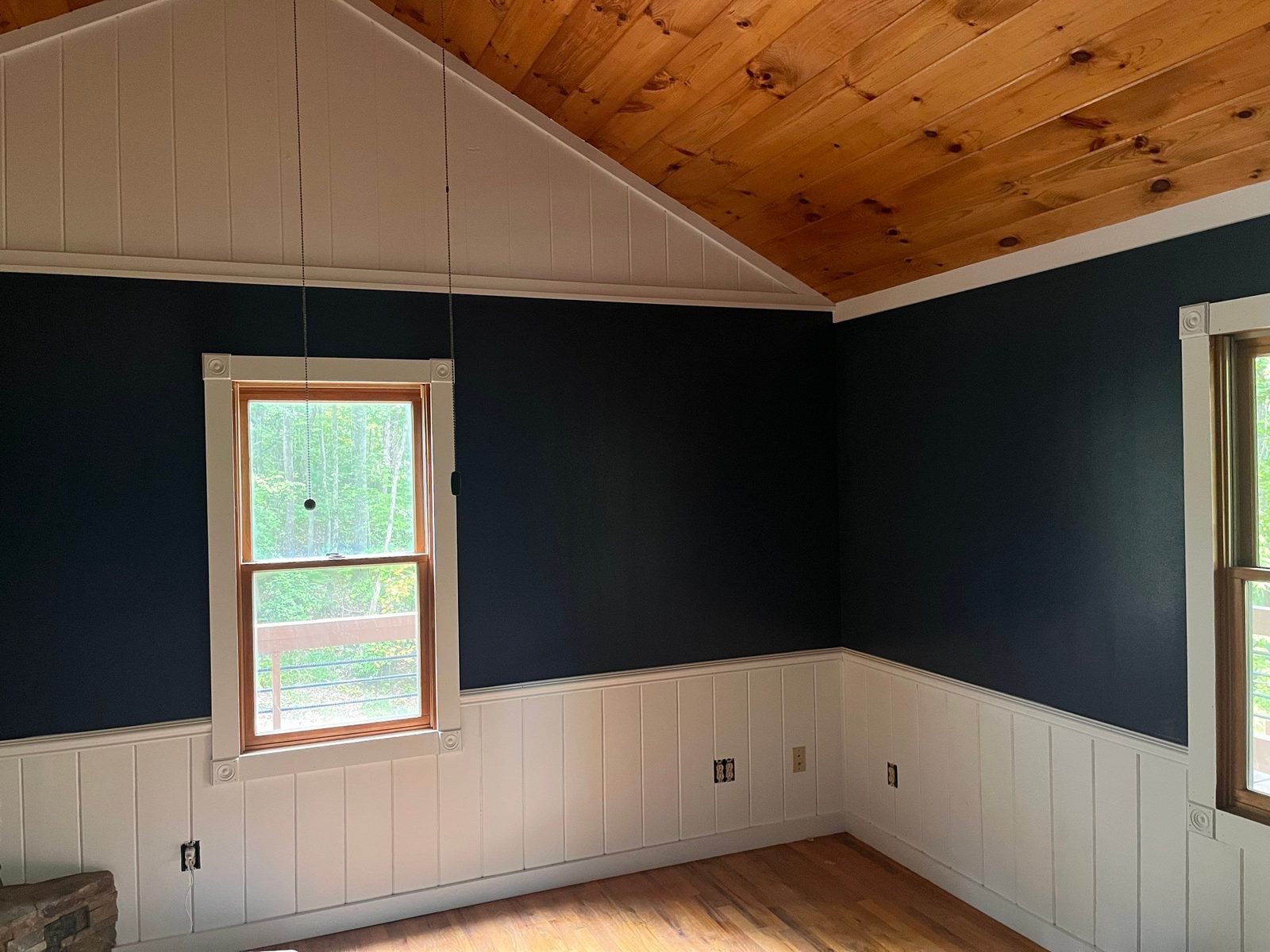 Cabin bedroom in Blue Ridge, GA painted deep navy above white wainscot under a vaulted pine ceiling