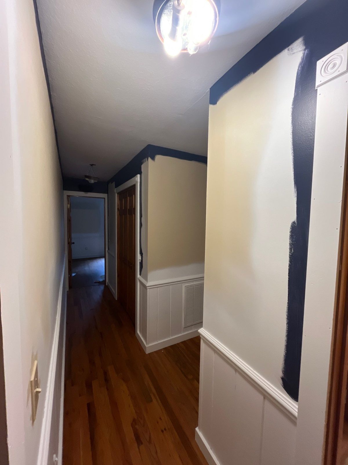 Cabin hallway in Blue Ridge, GA mid-repaint with navy cut in over beige walls and white wainscot