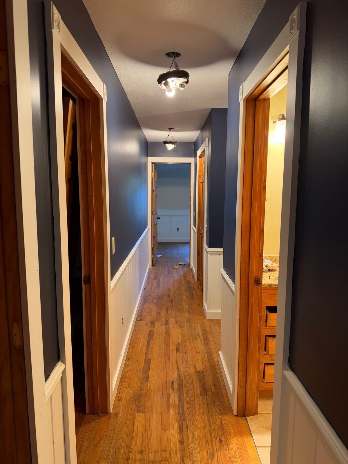 Finished cabin hallway in Blue Ridge, GA with navy walls, white wainscot and hardwood floors