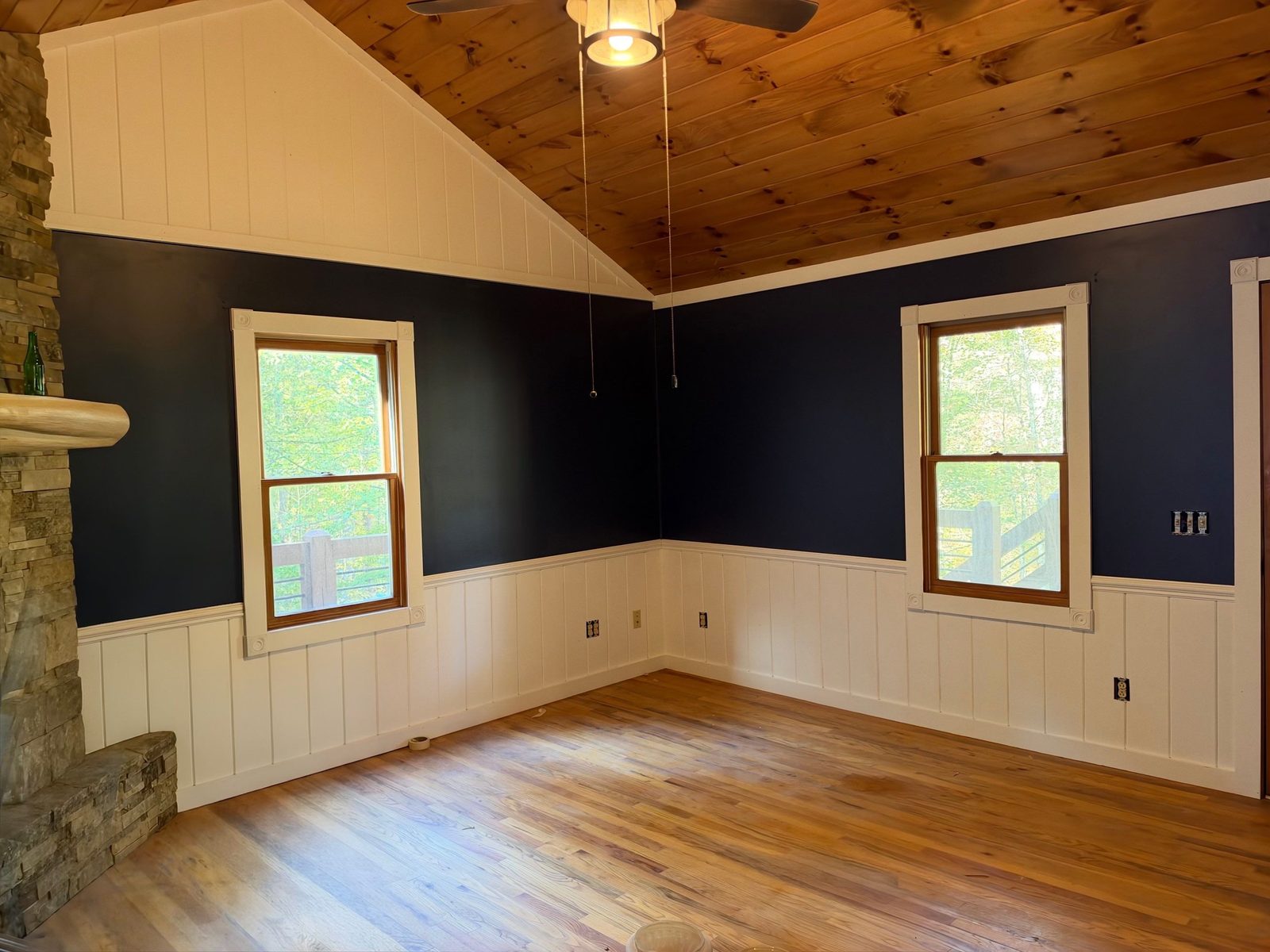 Blue Ridge cabin room painted navy with white wainscot, wood trimmed windows and a stone wall
