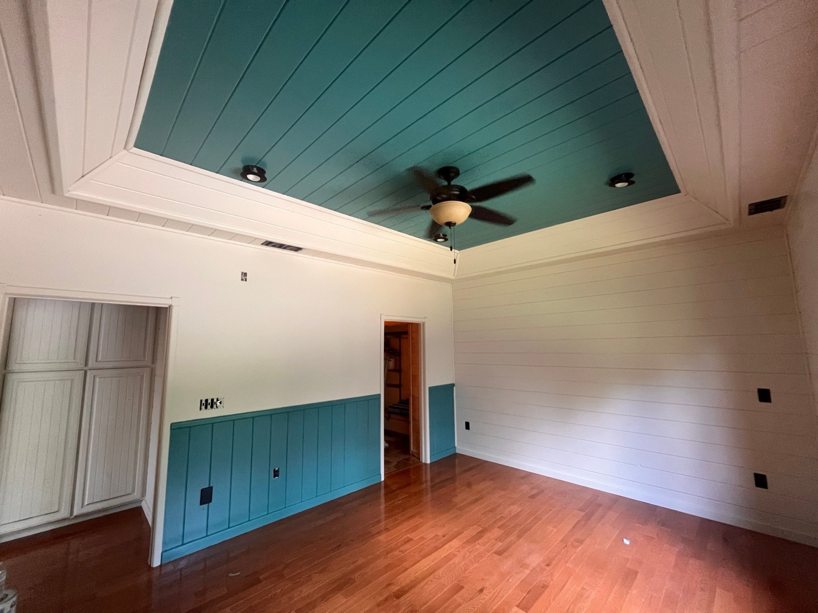 Cabin bedroom with a teal painted ceiling and matching teal wainscot