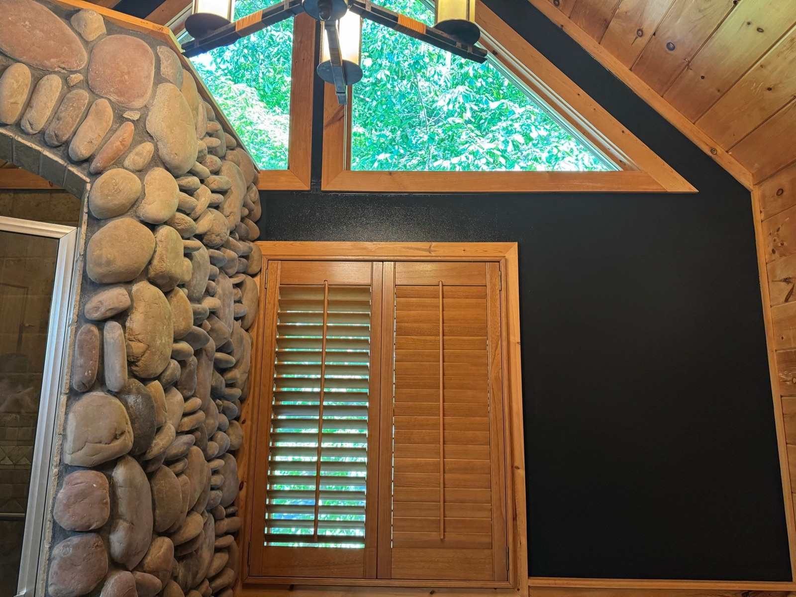 Black painted accent wall beside a river-rock chimney in a North Georgia cabin