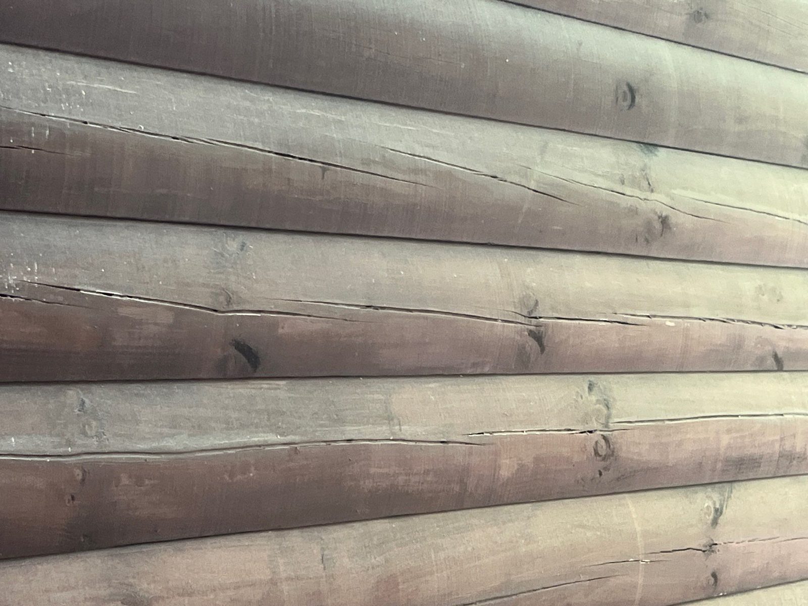 Close-up of weathered, checked log siding on a Cherry Log cabin before staining