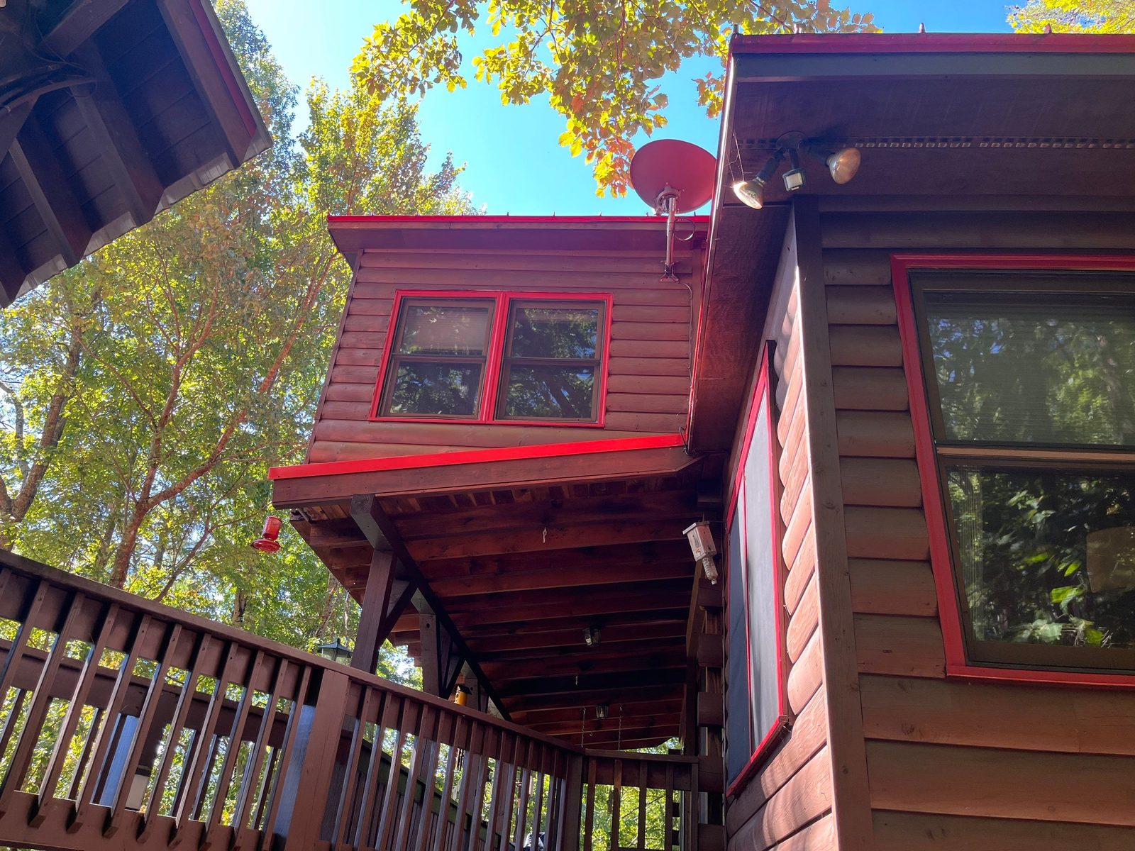 Stained cabin dormer with red window trim and red metal roof in Cherry Log, GA