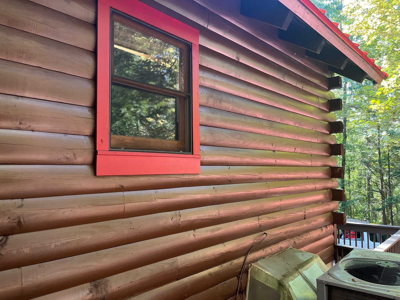 Red painted window trim on a freshly stained log wall in Cherry Log, GA