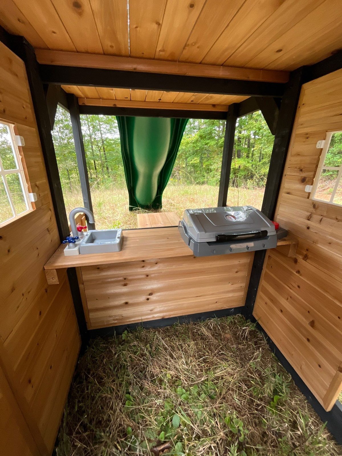 Playset clubhouse with a built-in play kitchen sink and stove, cedar walls and windows