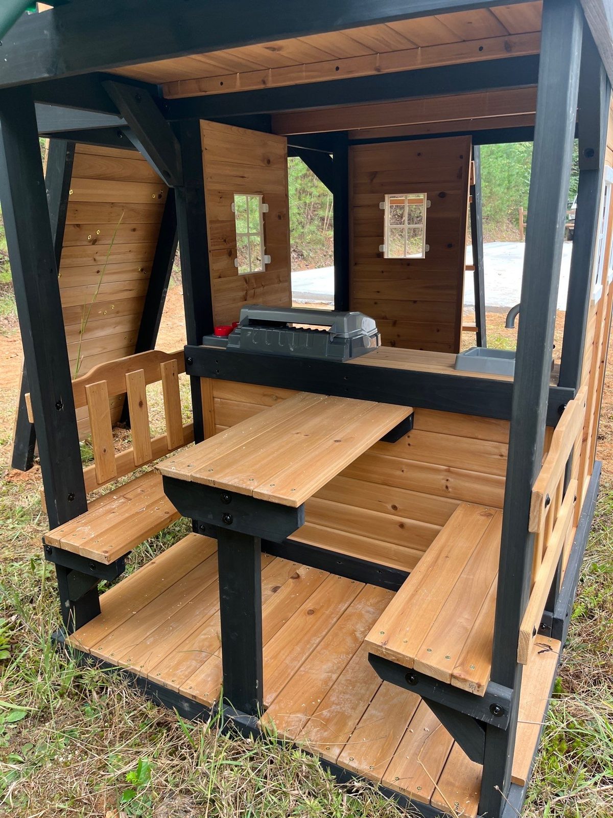 Picnic table and benches under the clubhouse deck of an assembled wooden playset